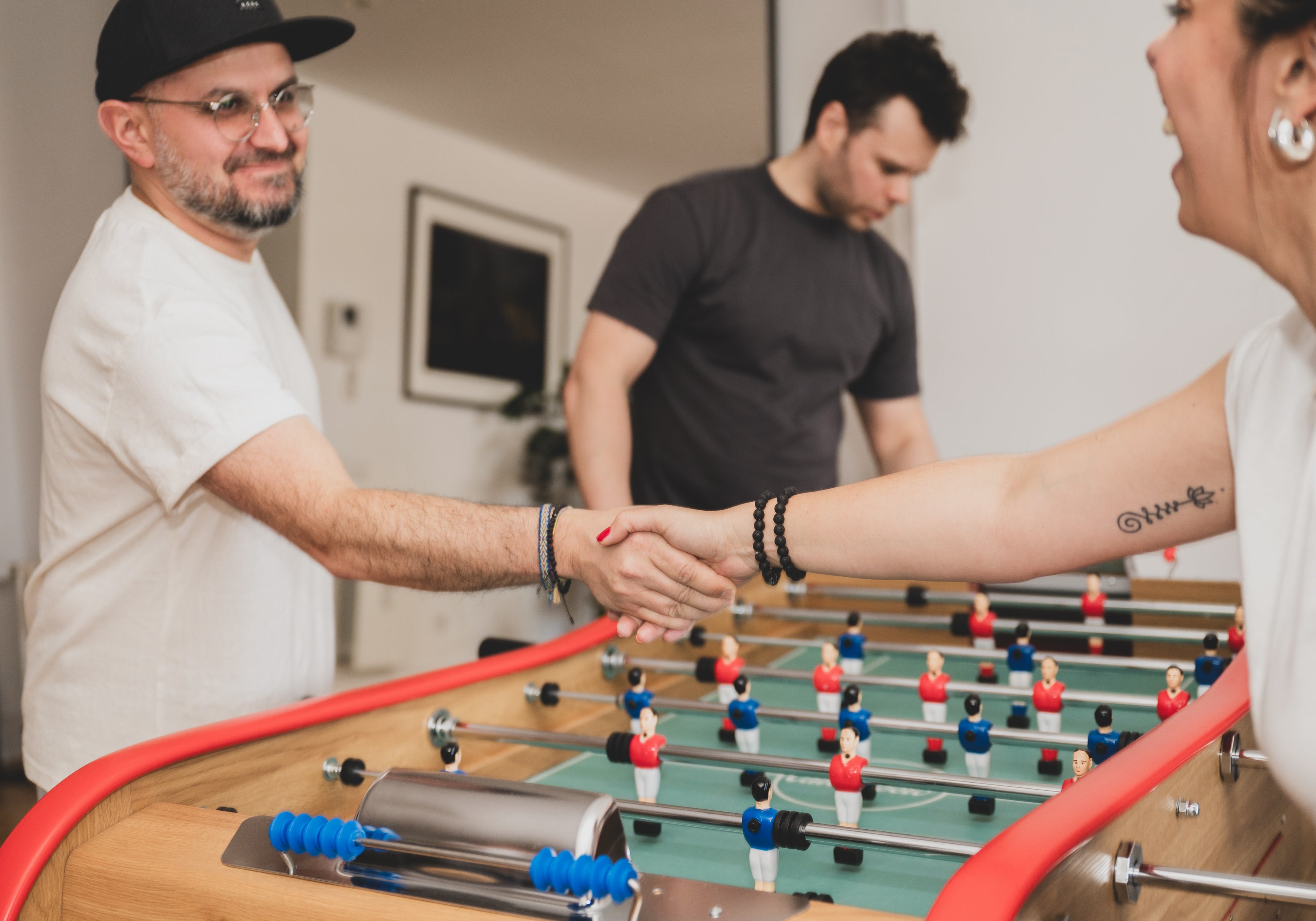 Des personnes échangent une poignée de main autour d’un babyfoot